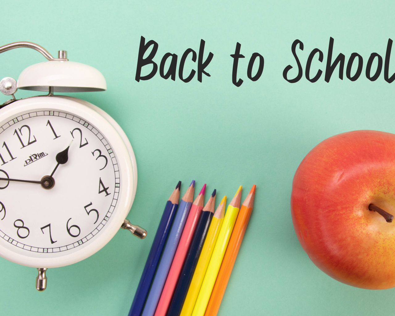 Будильник, карандаши и яблоко на фоне с надписью пора в школу