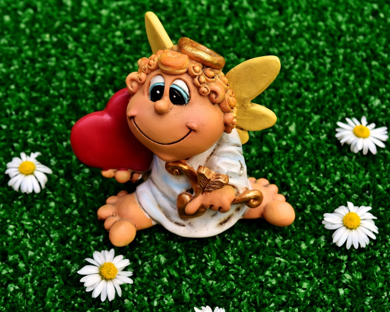 Статуэтка ангела на зеленой траве с белыми ромашками