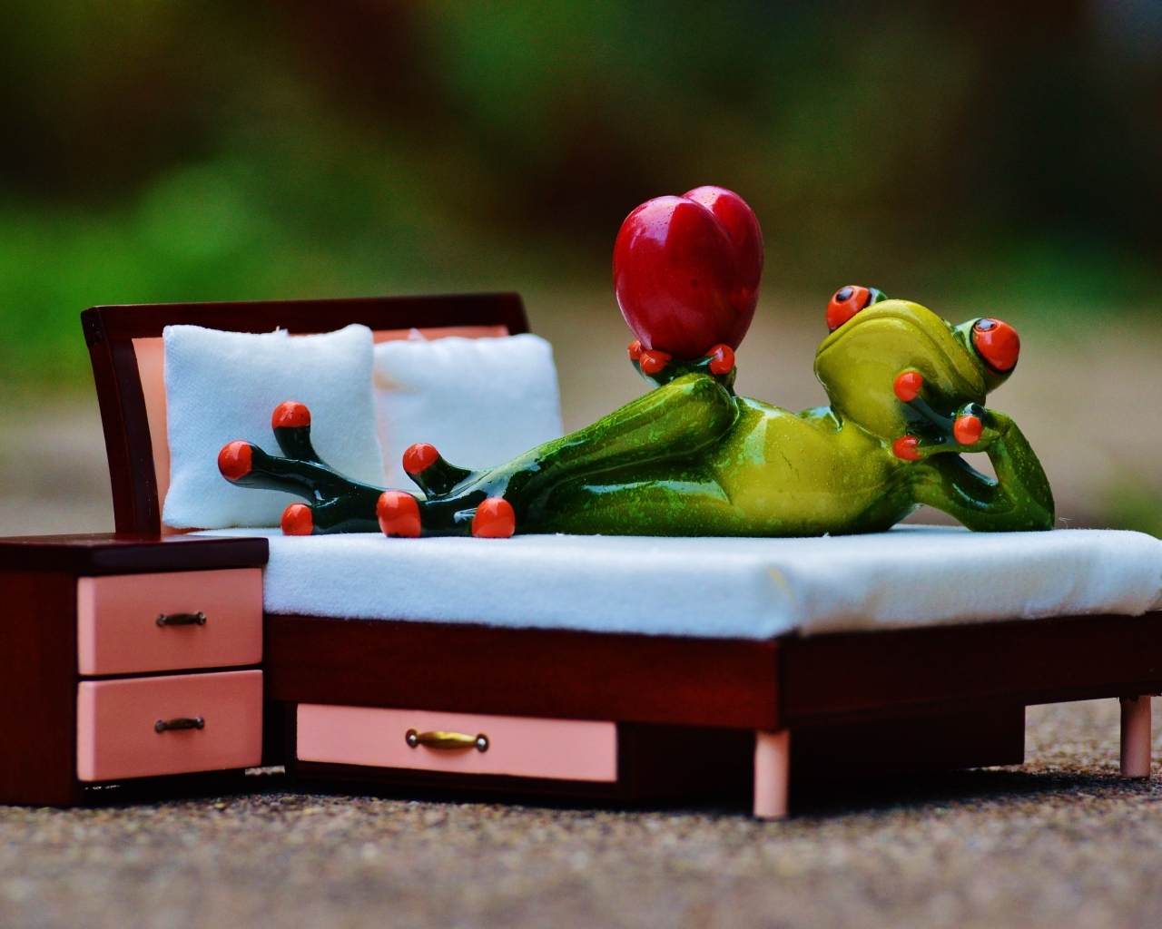 Фигурка зеленая лягушка с красным сердцем на кровати
