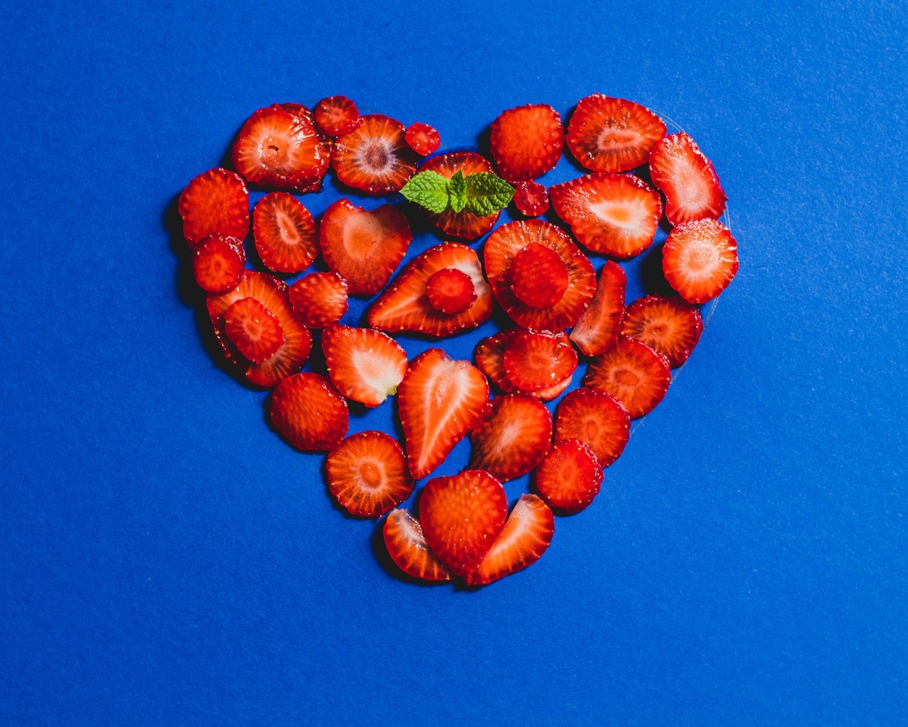 Сердце из сушеной клубники на синем фоне