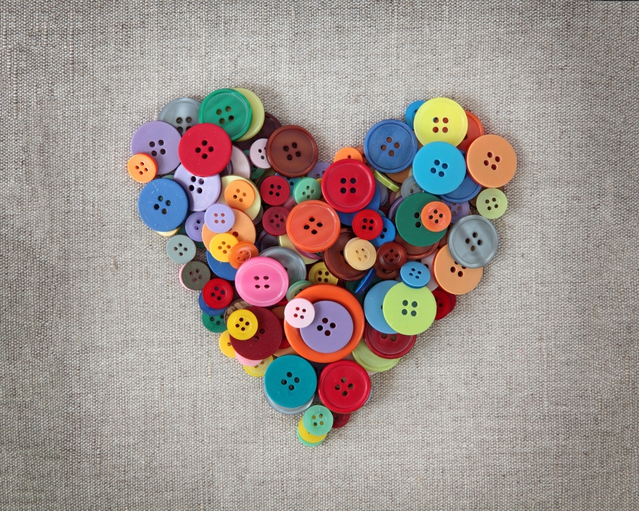 Сердце из разноцветных пуговиц на ткани 