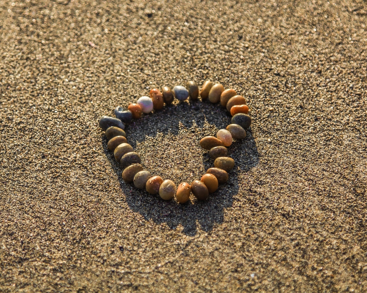 Сердце из камней на морском песке летом