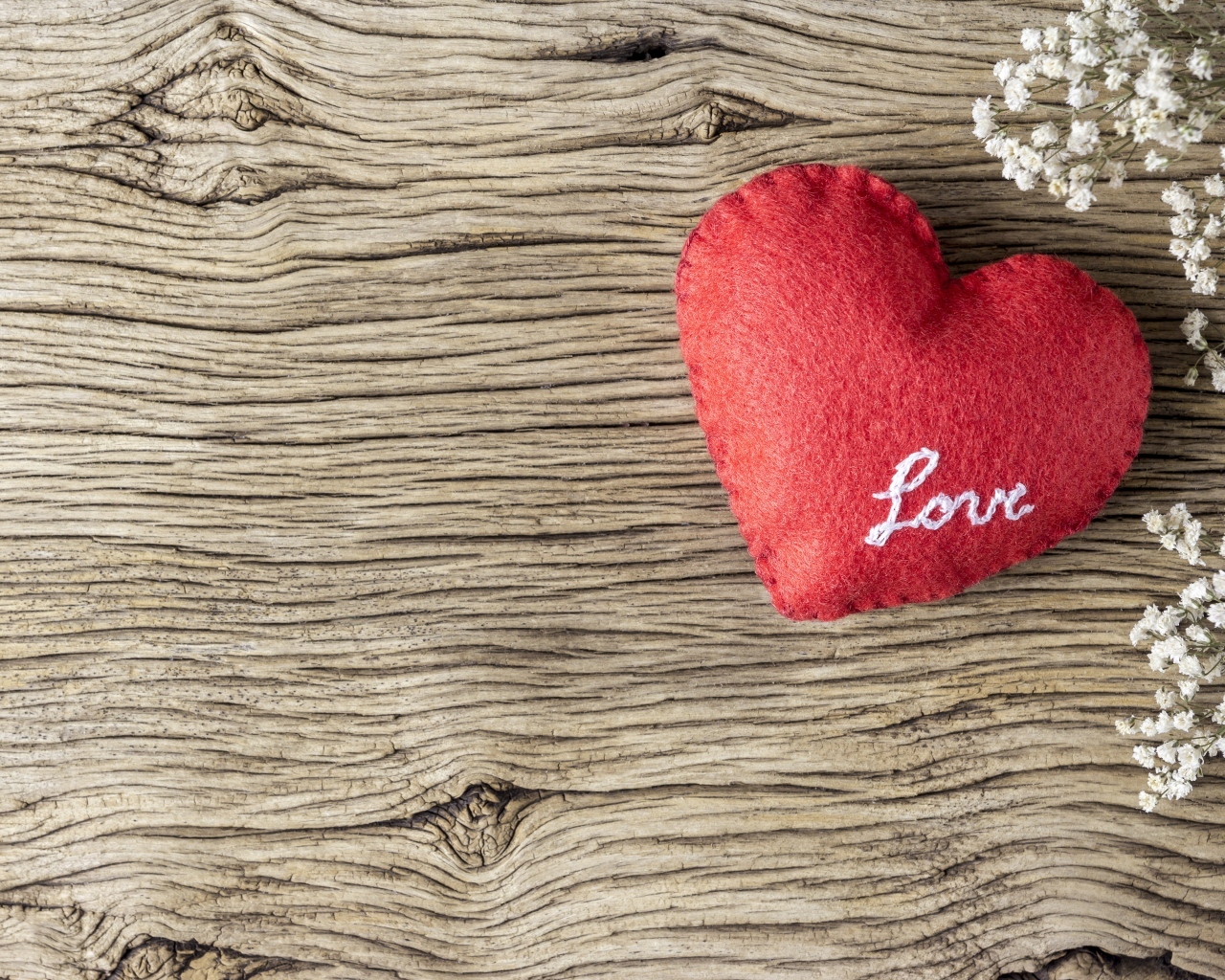 Красное тканевое сердце с цветами на деревянном столе