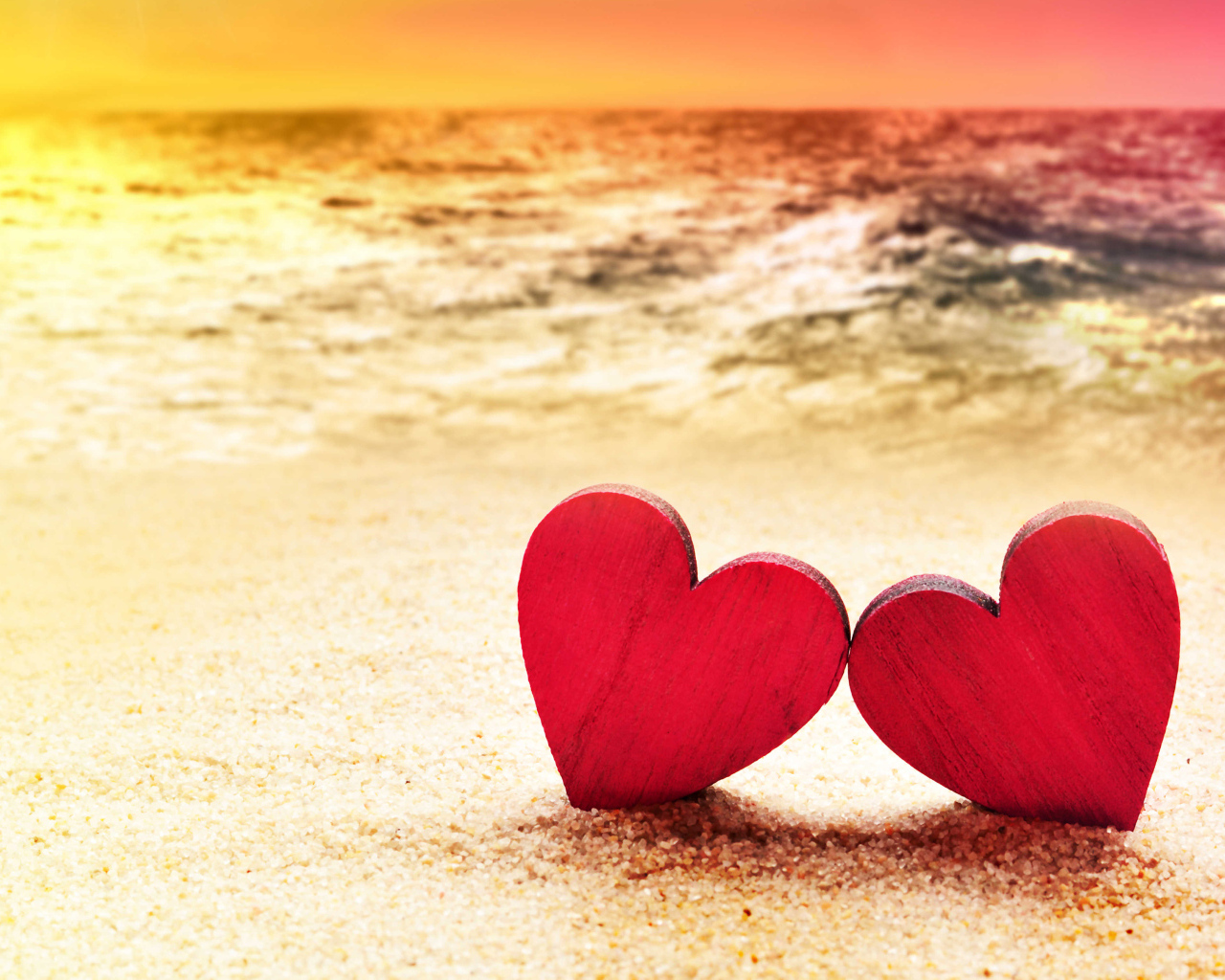 Два красных сердечка на песке на пляже