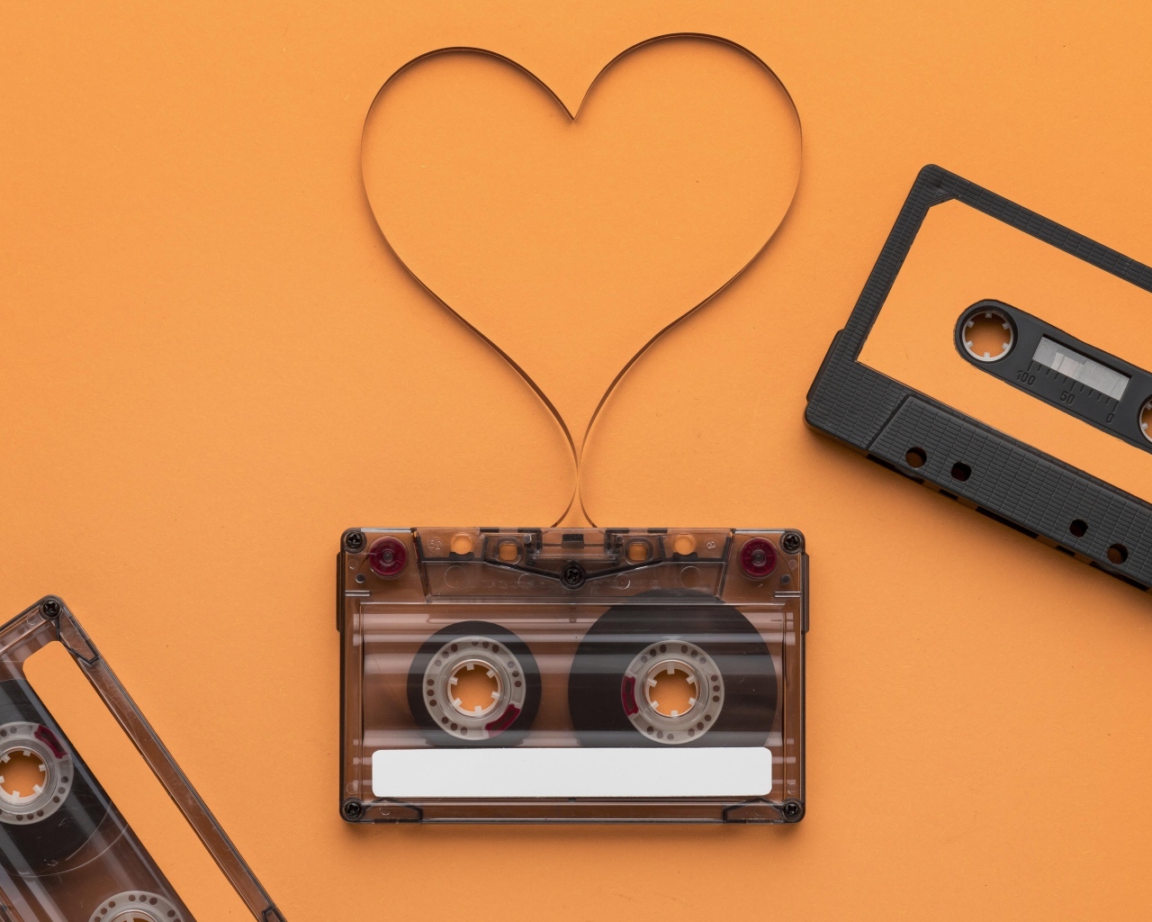 Кассеты и сердце из ленты на оранжевом фоне