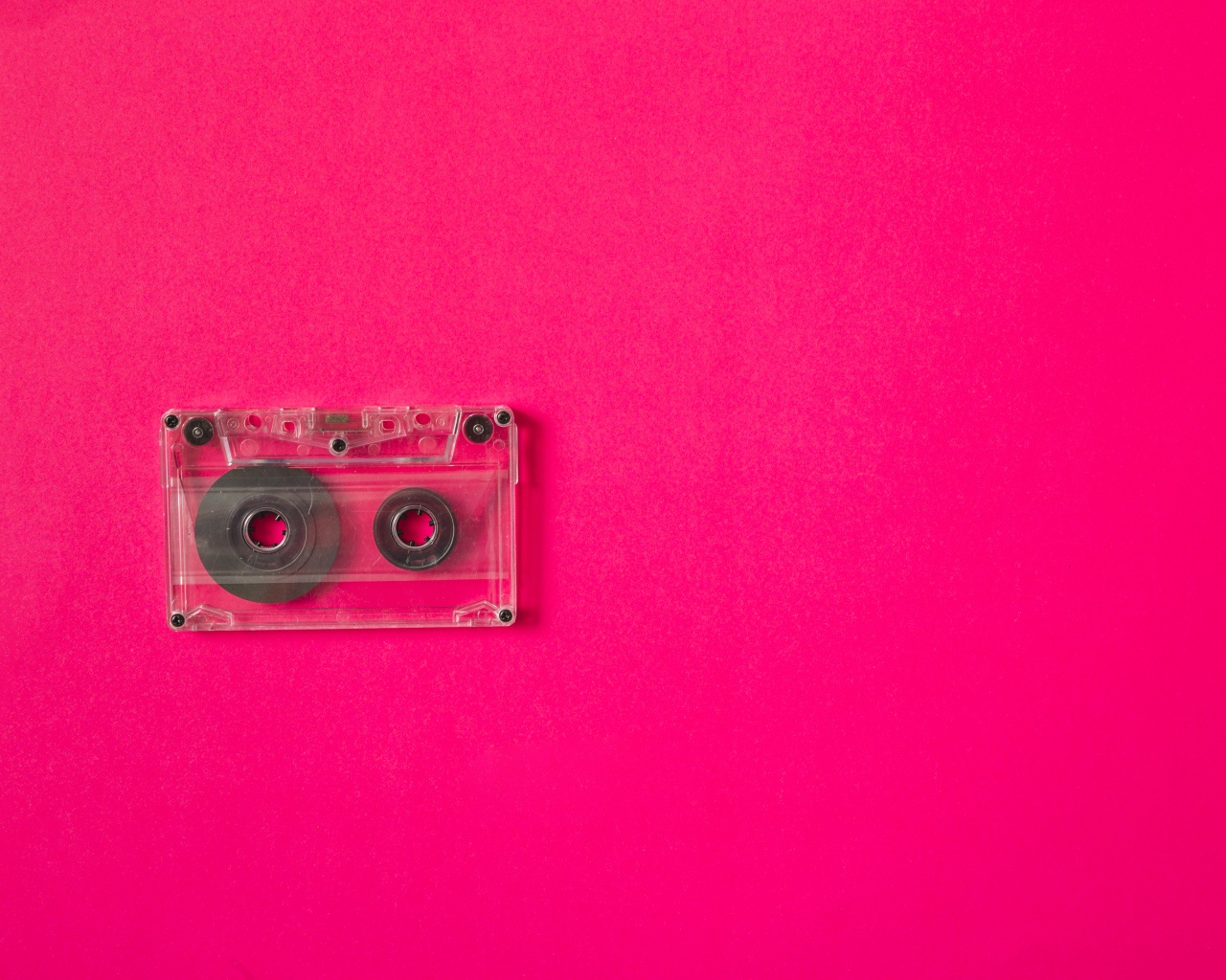 Маленькая магнитофонная кассета на розовом фоне