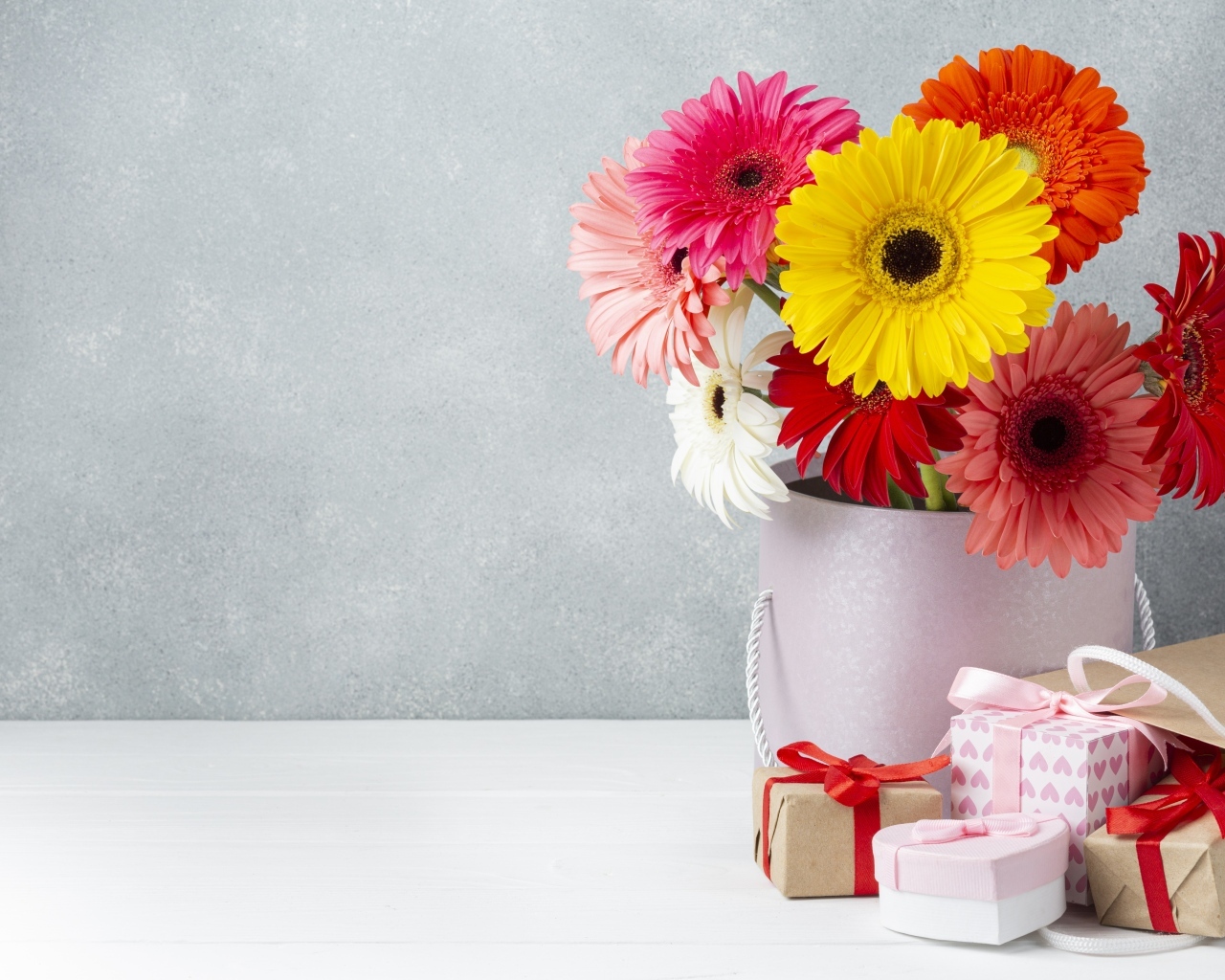 Букет разноцветных цветов герберы на столе с подарками