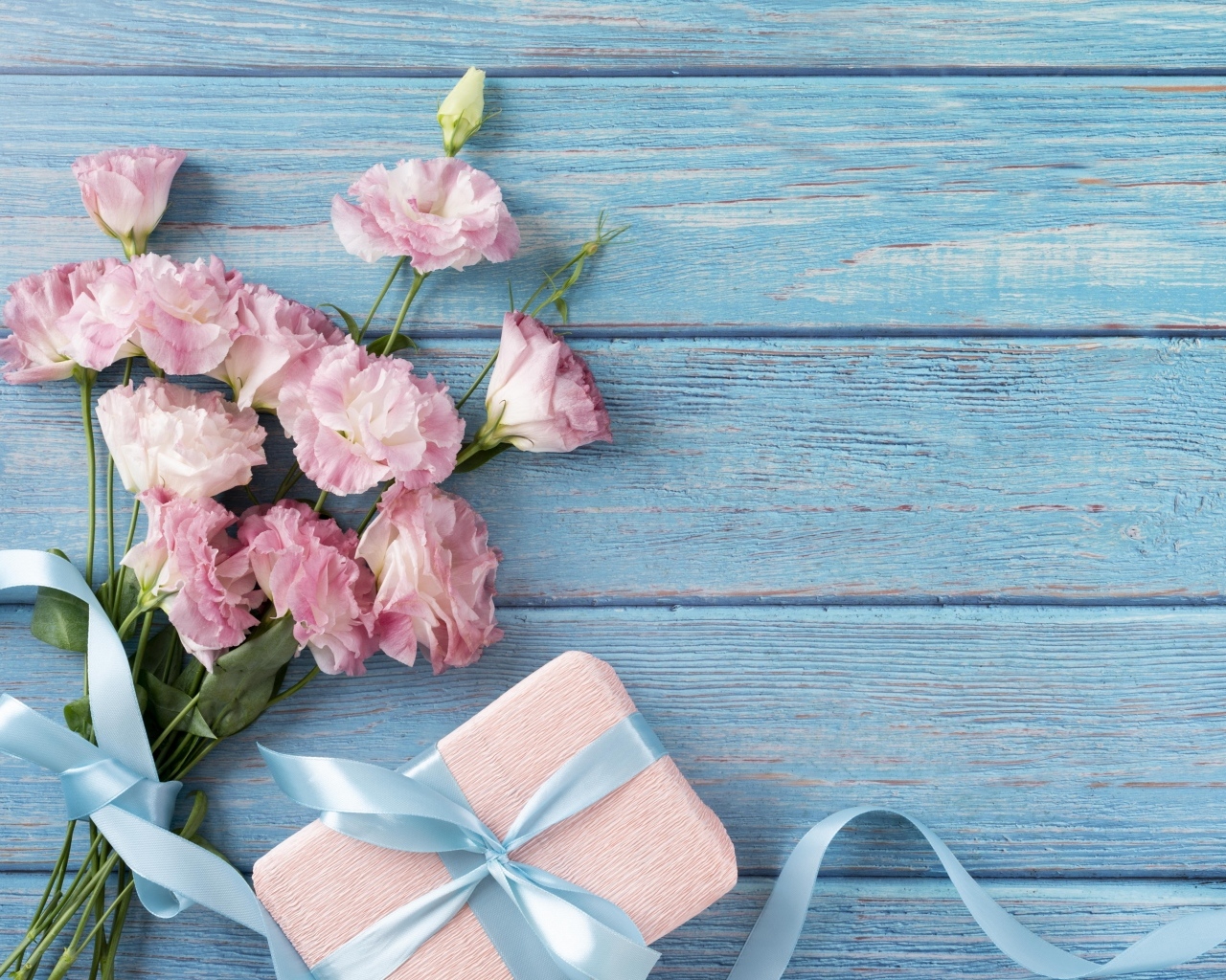 Букет розовых цветов эустомы с подарком на голубом столе