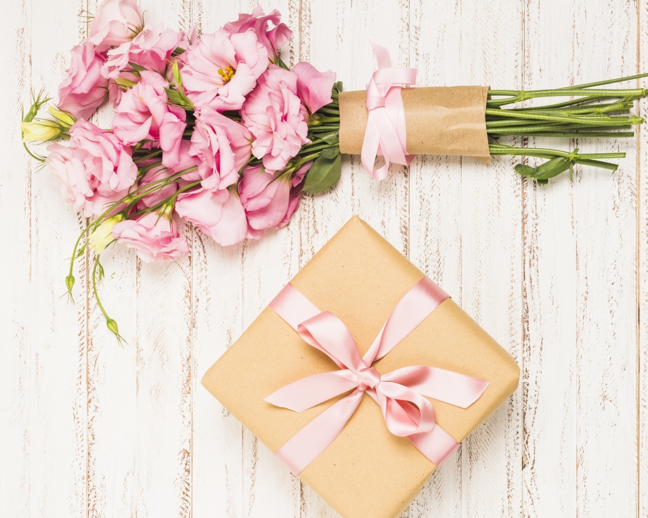 Букет розовых цветов эустомы с подарком на деревянном фоне