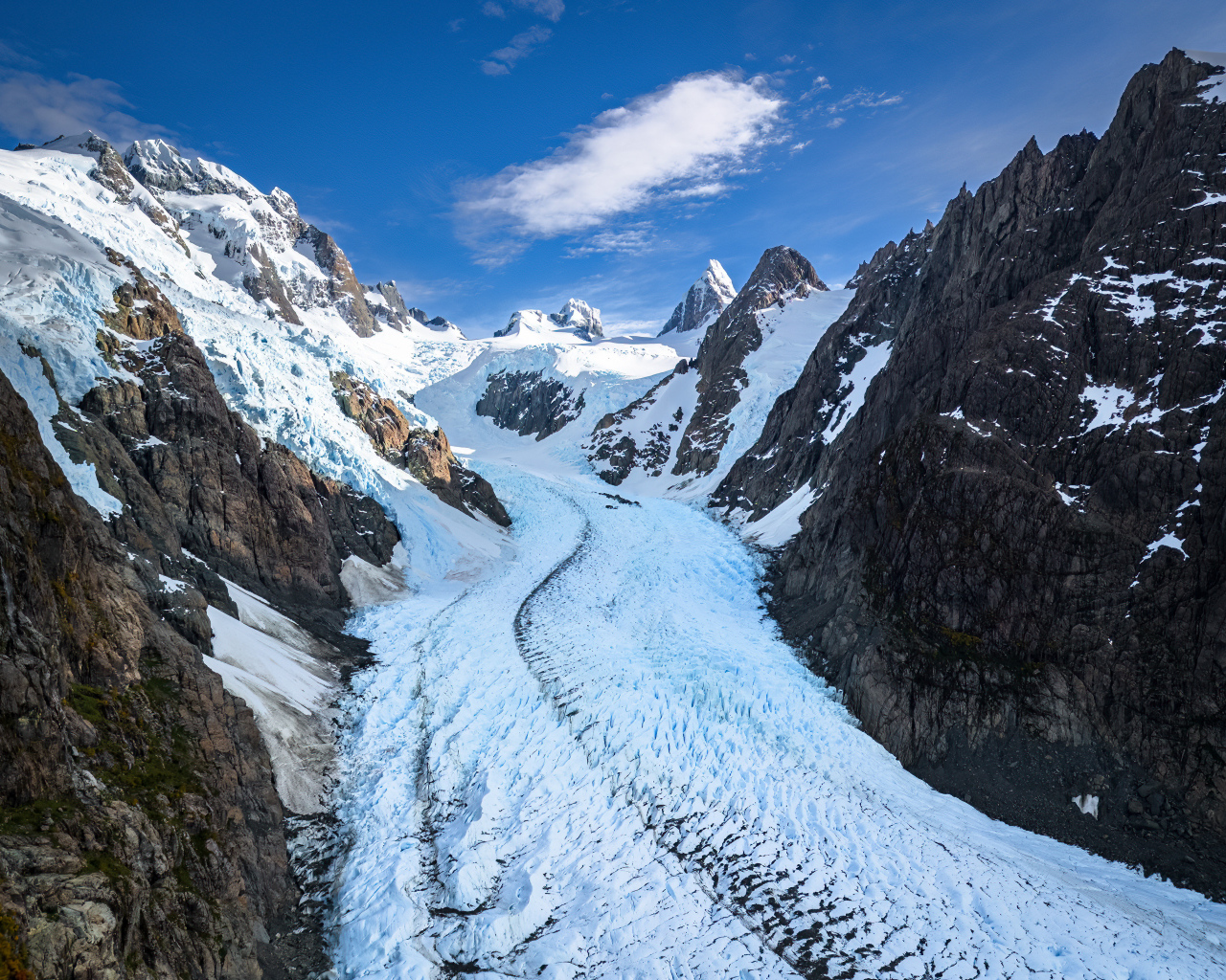 Заснеженная заледеневшая дорога между гор