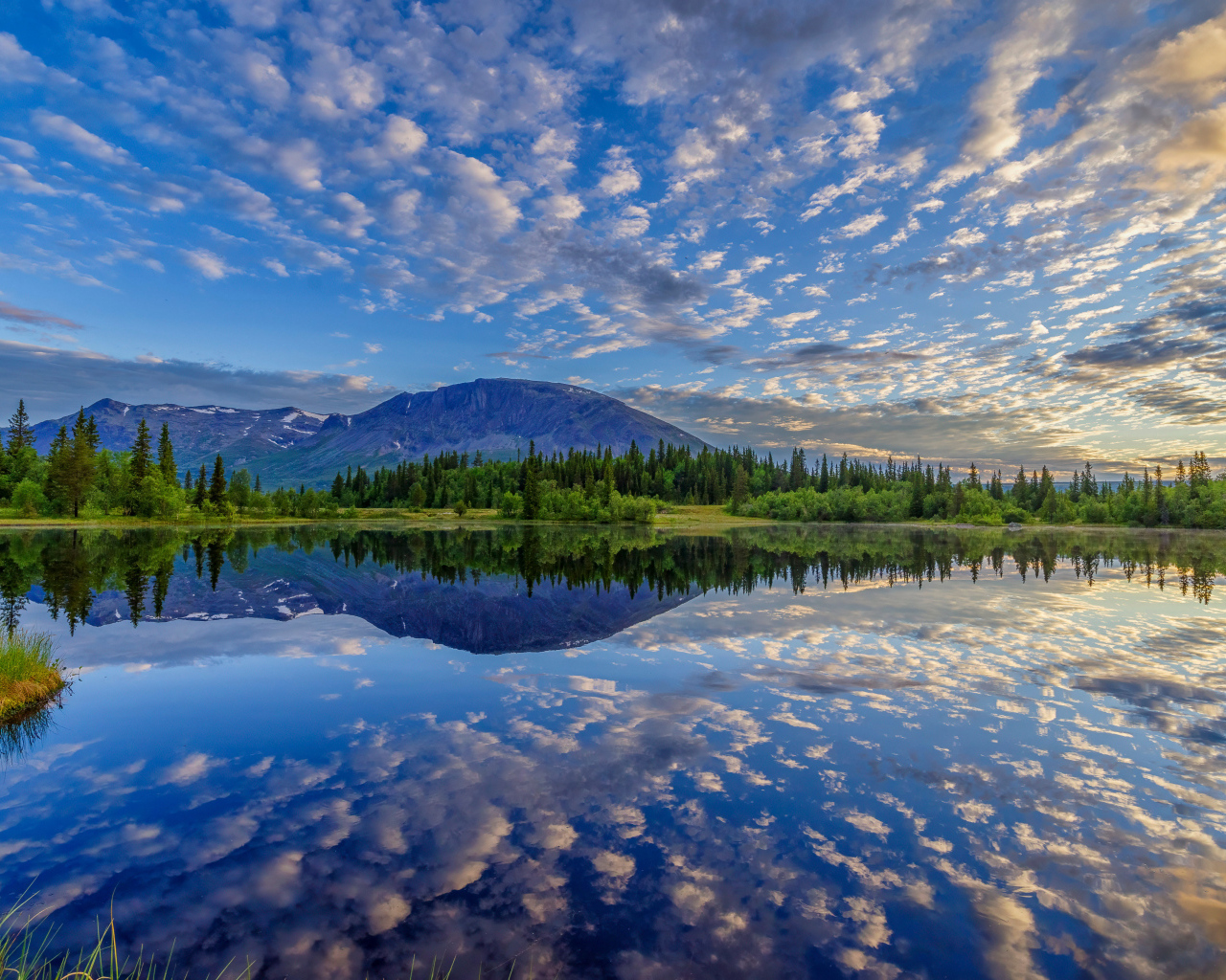 Красивое небо с облаками отражается в озере у гор