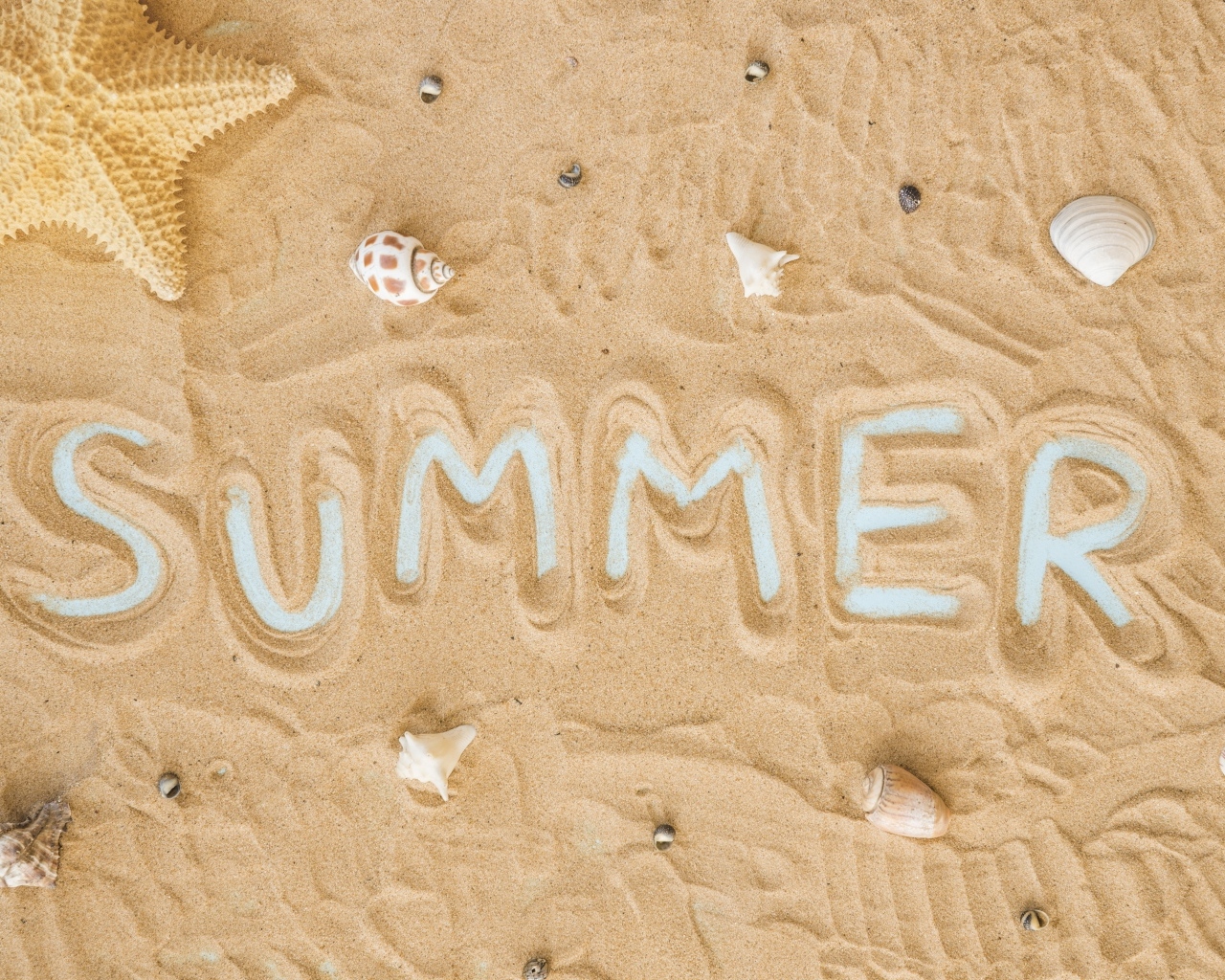 Надпись лето на песке с ракушками