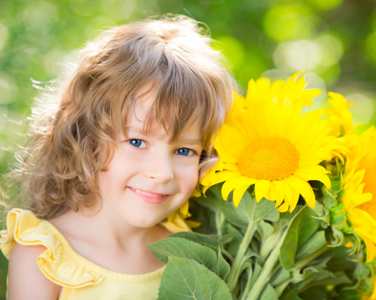 Красивая голубоглазая девочка с букетом подсолнухов
