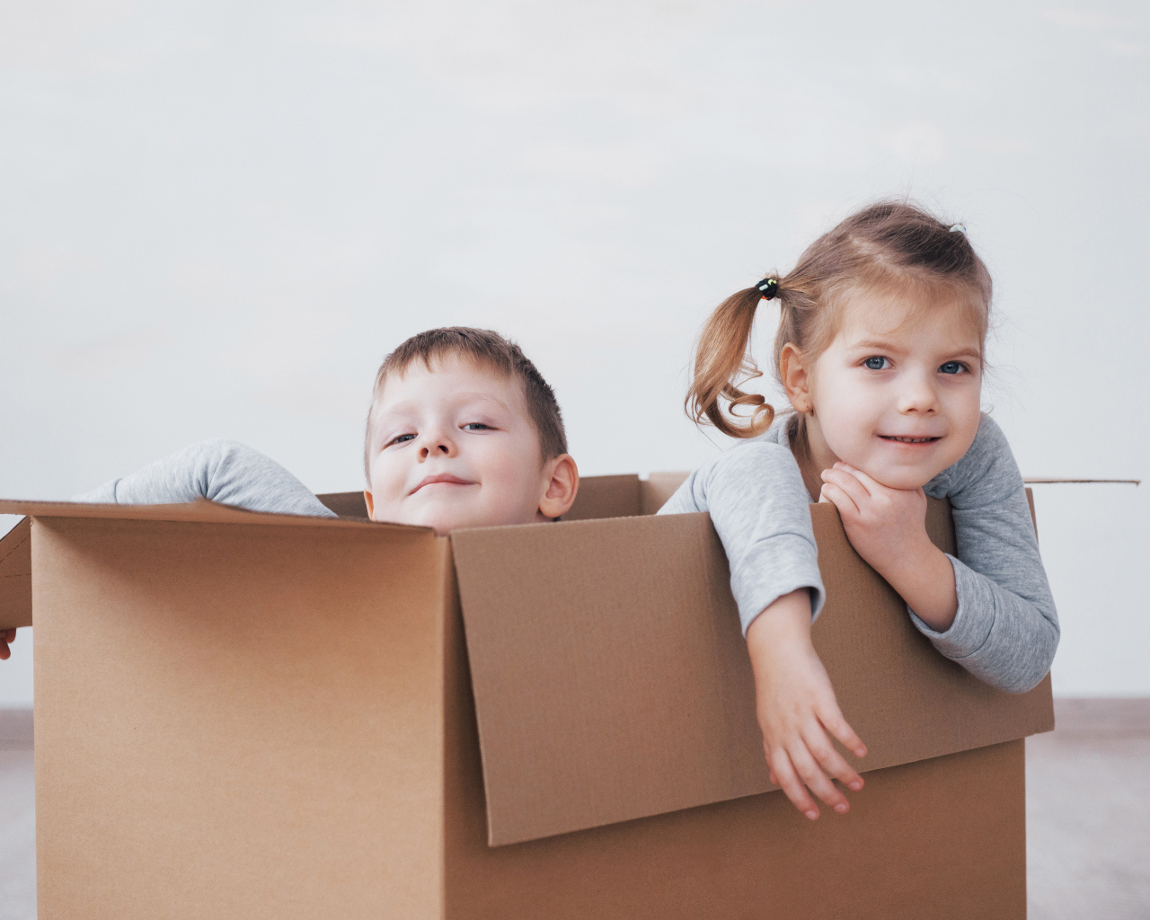 Брат и сестра сидят в картонной коробке