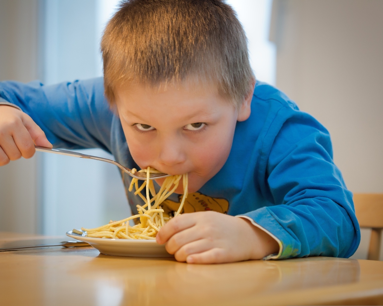 Маленький мальчик ест макароны