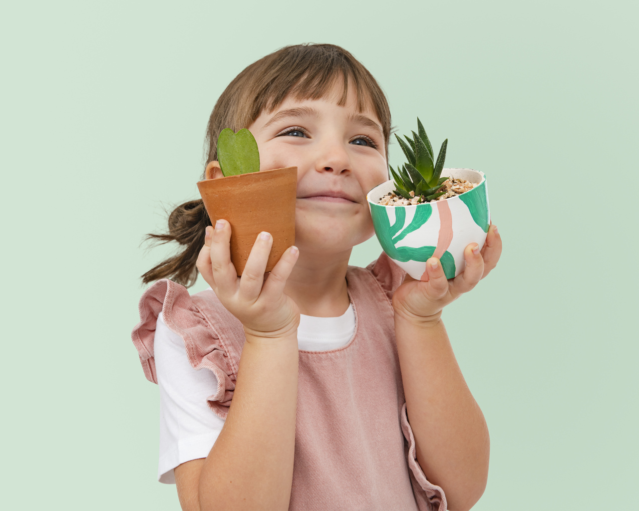 Маленькая девочка с комнатными цветами в руках