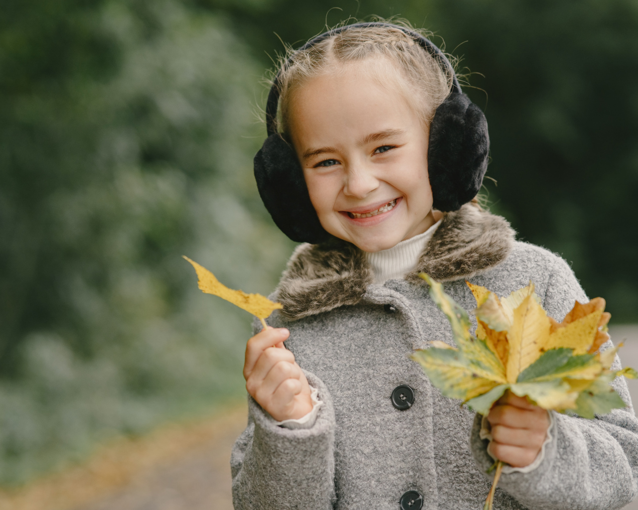Улыбающаяся девочка с опавшими листьями в руках