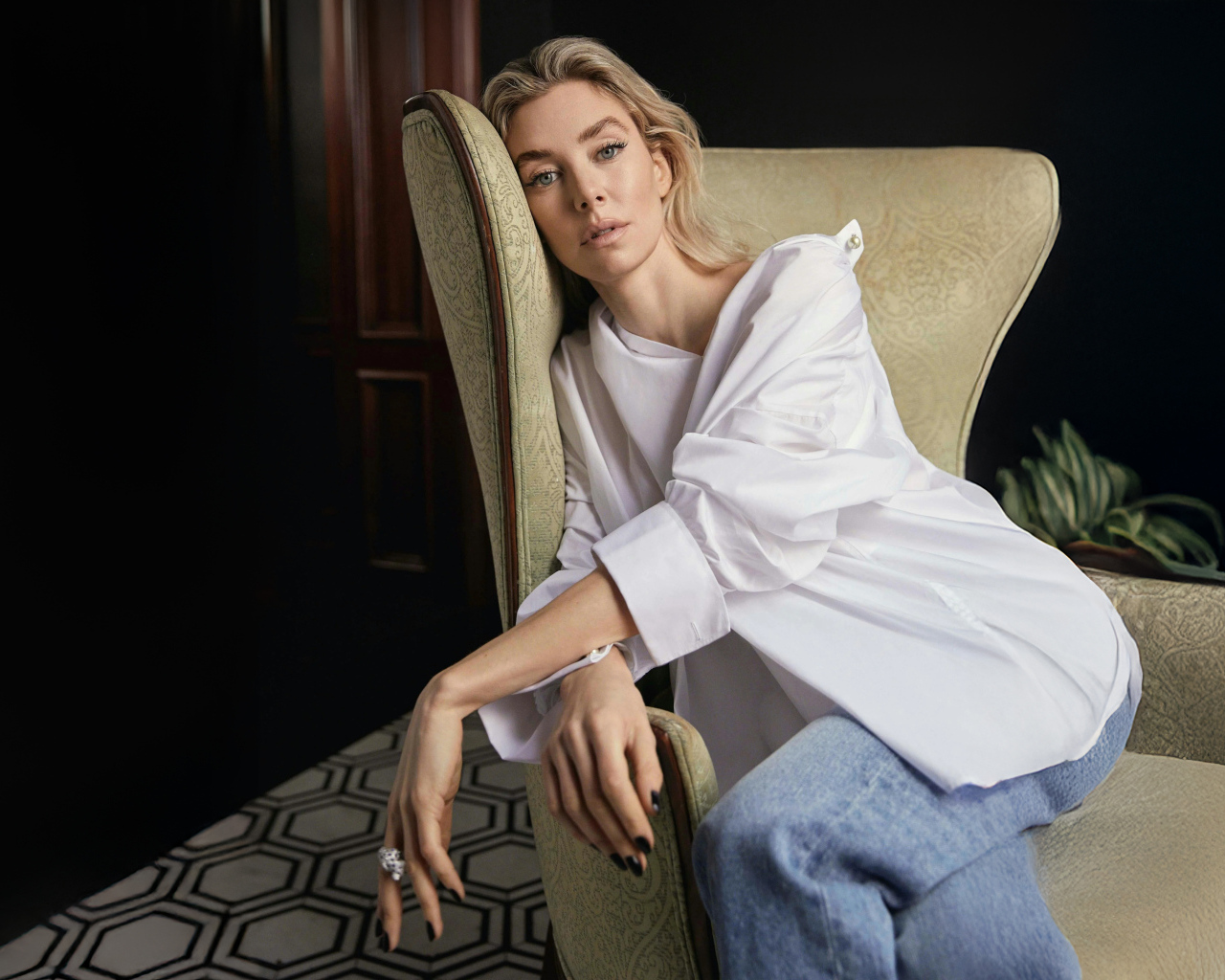 Актриса Ванесса Кирби в белой рубашке сидит на кресле