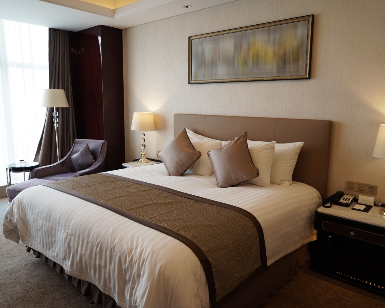 Большая кровать в комнате с картиной на стене