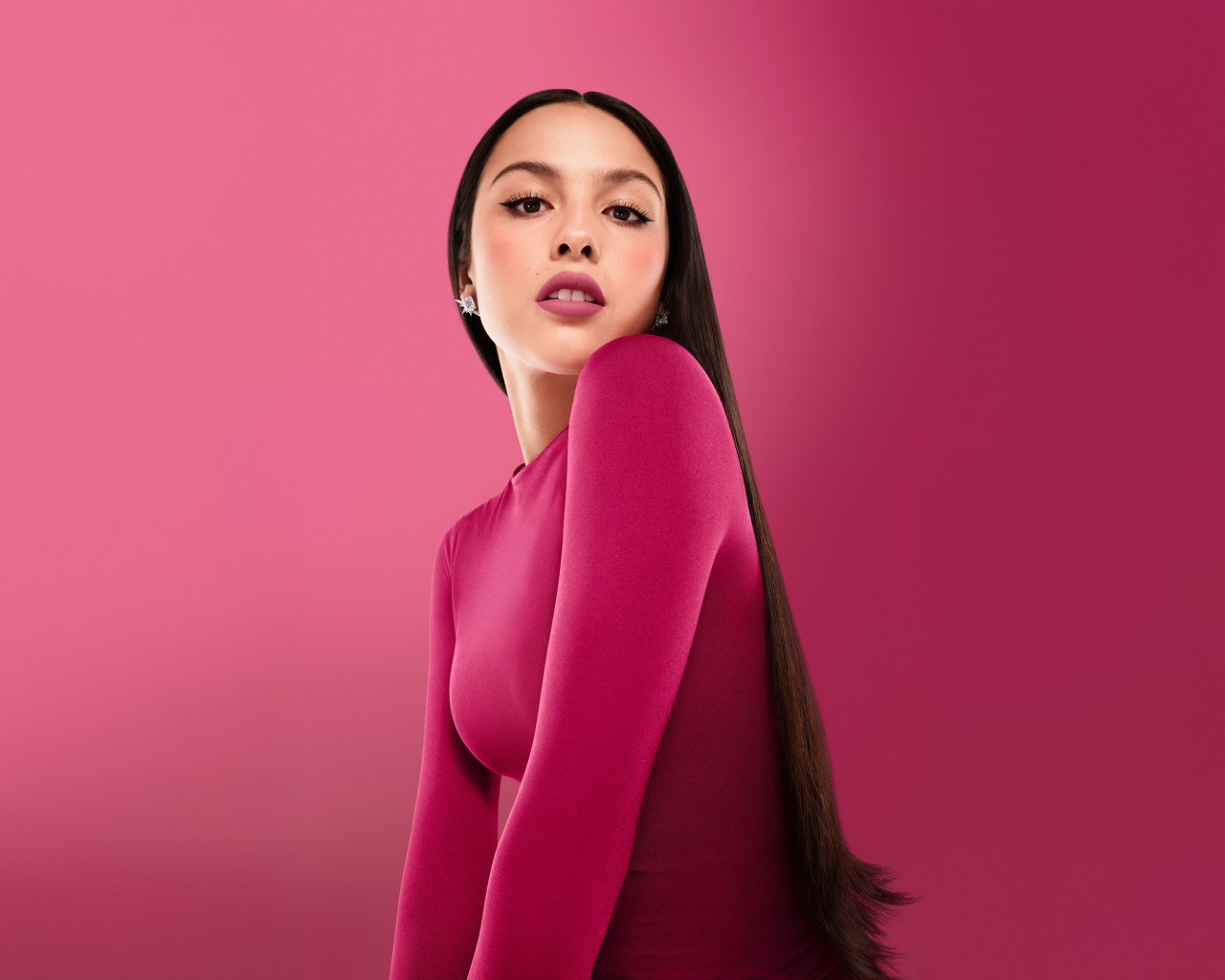 Длинноволосая актриса Оливия Родриго на розовом фоне
