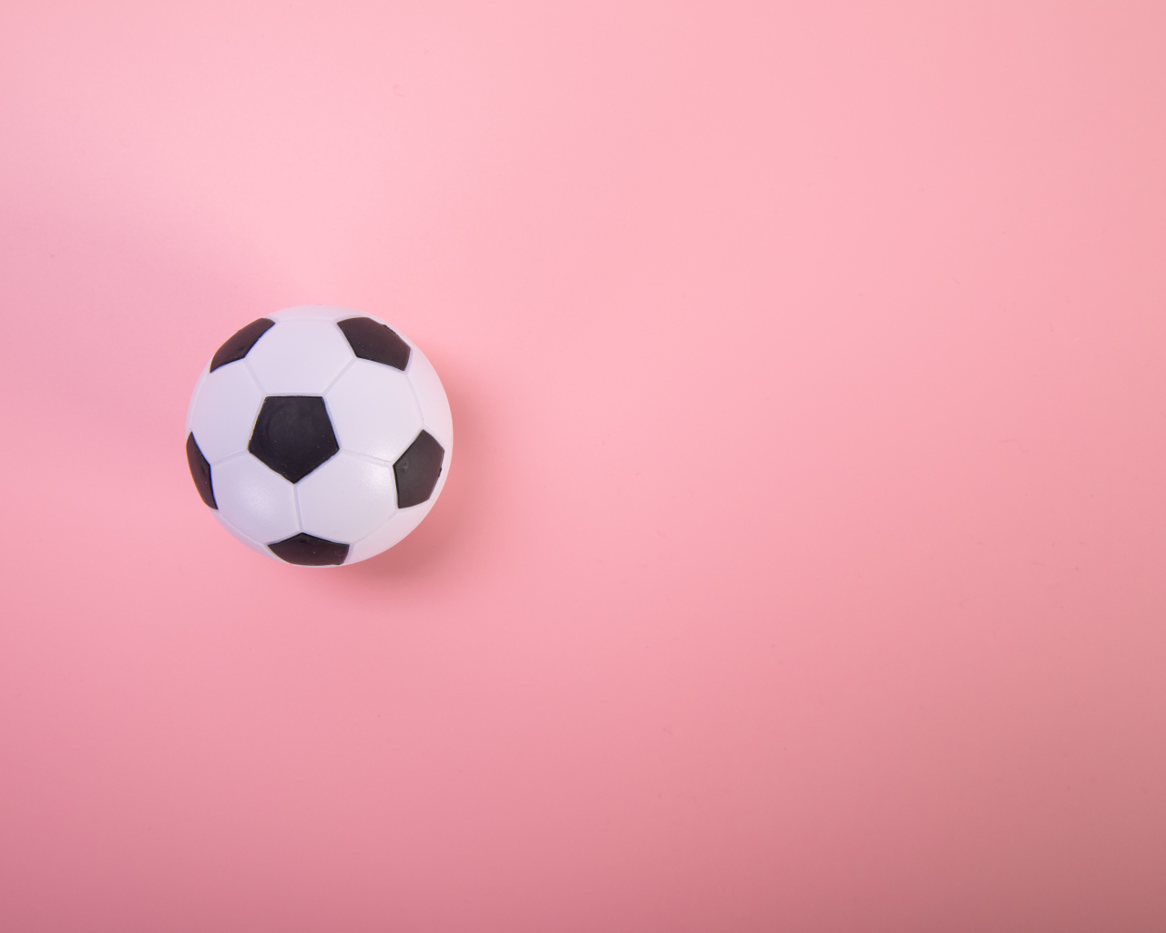 Футбольный мяч на розовом фоне