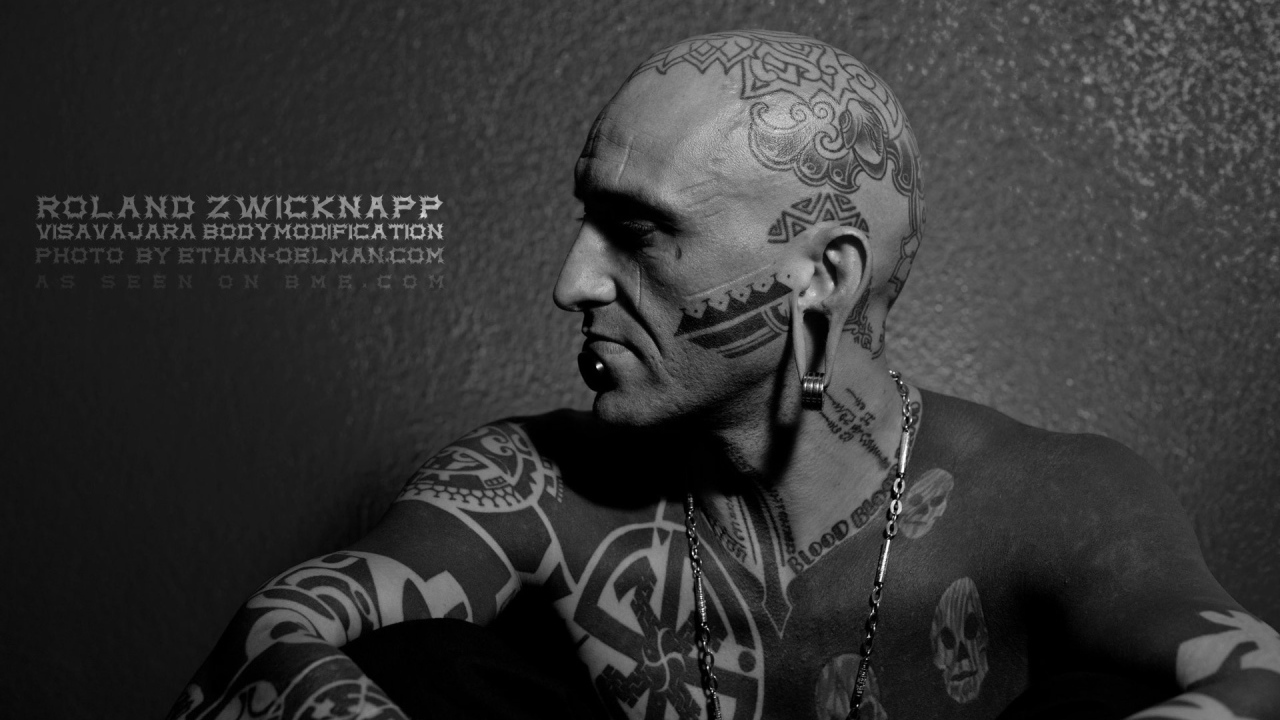 Мужчина с пирсингом в губе и татуировками