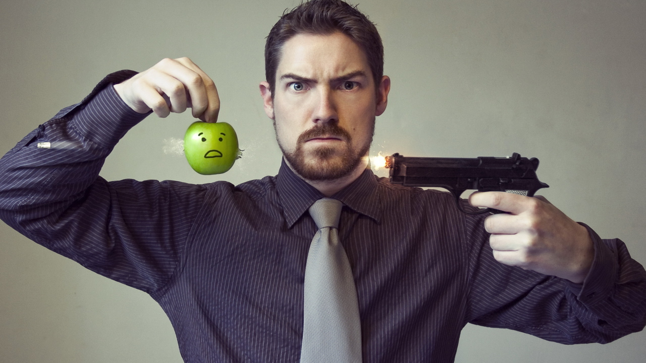 Мужчина стреляет в яблоко