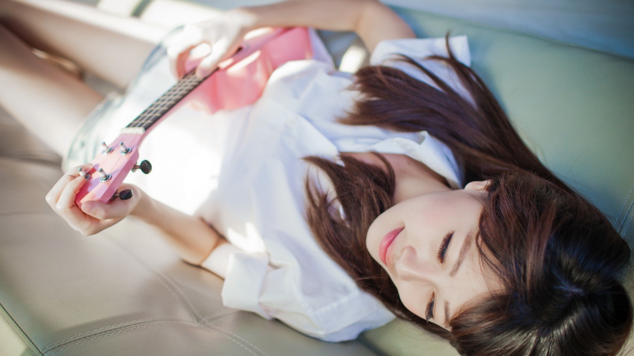 Брюнетка и розовая гитара на диване