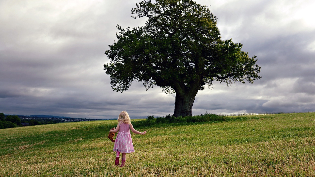 Маленькая девочка бежит к дереву