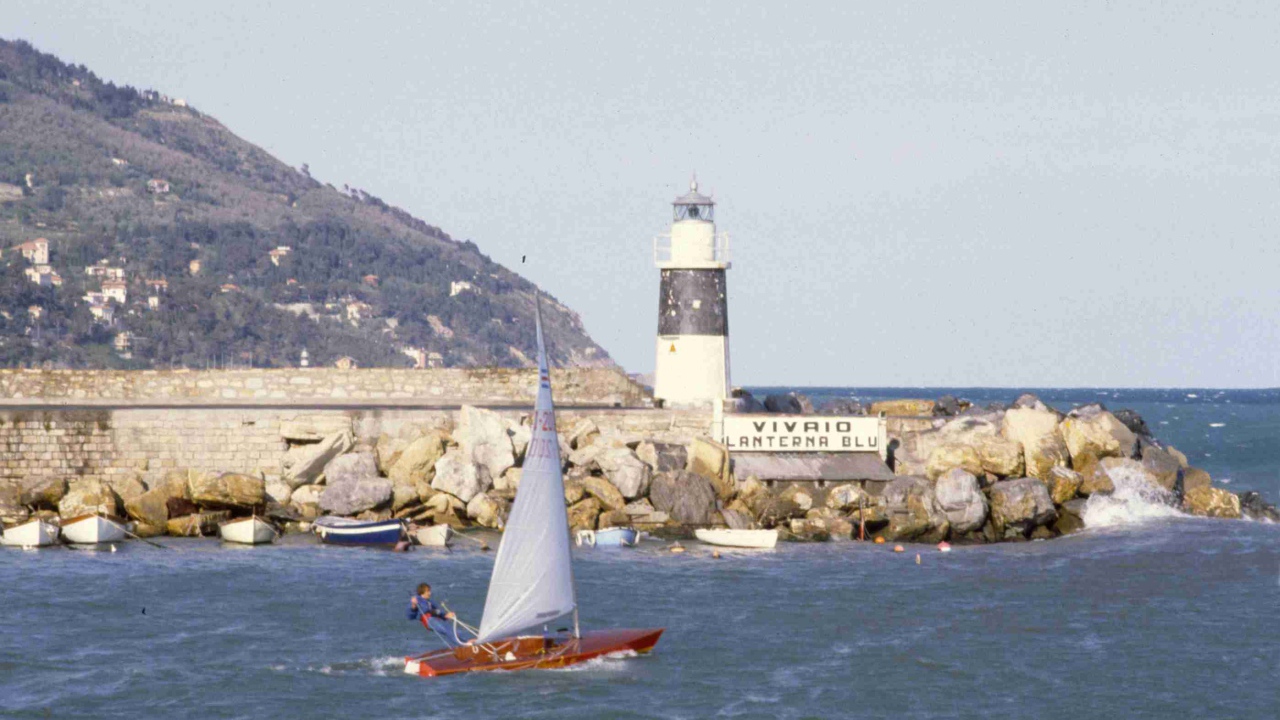 Лодка на фоне маяка на курорте Империя, Италия