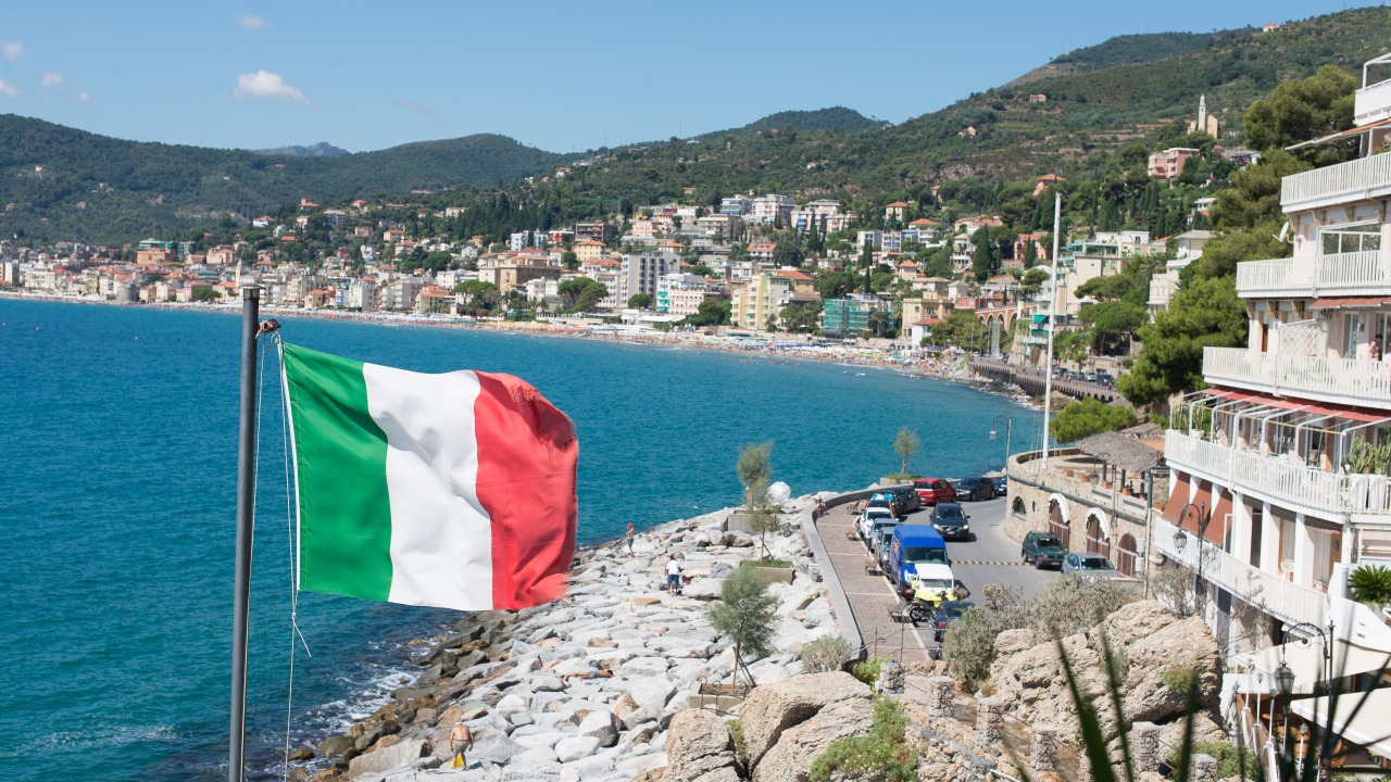 Флаг на фоне пляжа на курорте Алассио, Италия