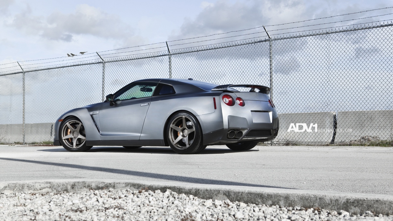 Серый Nissan Skyline GT-R R35 у забора из сетки
