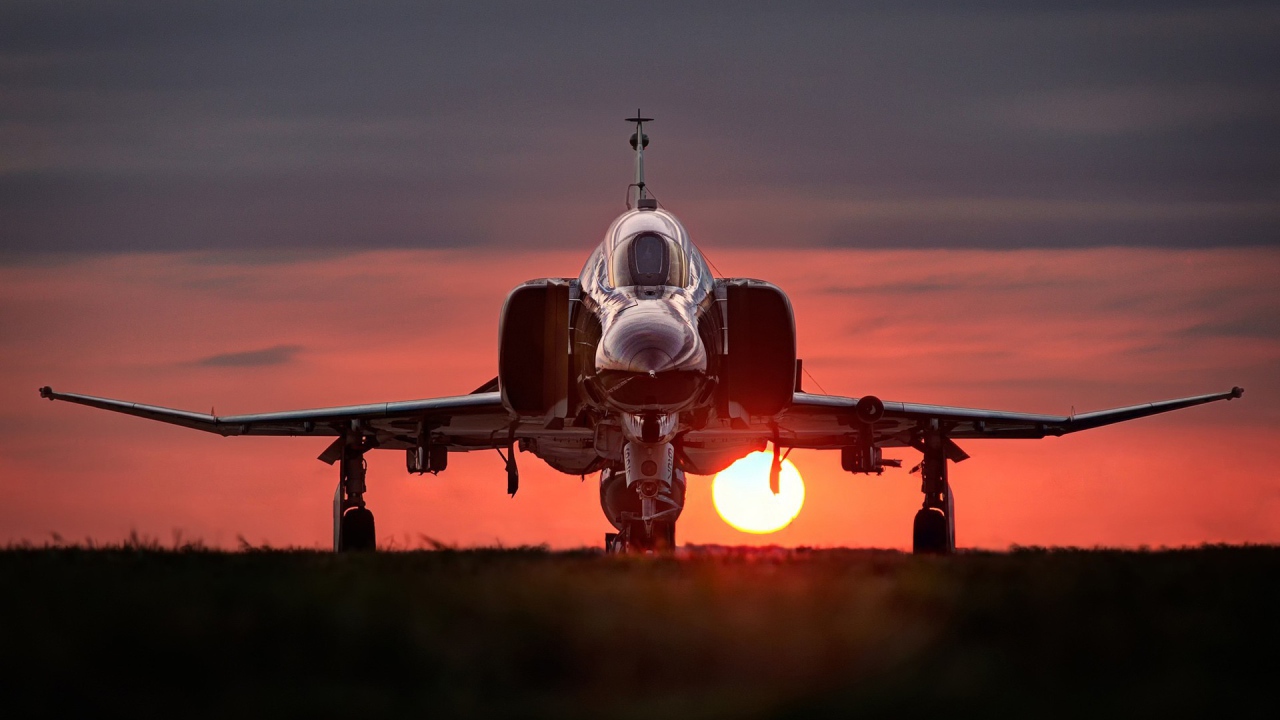 Истребитель F-4 Phantom II стоит на фоне заката