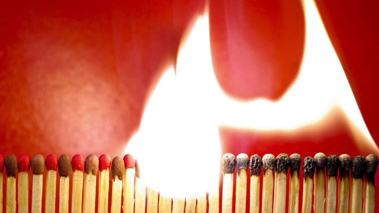 Горящий ряд спичек на красном фоне