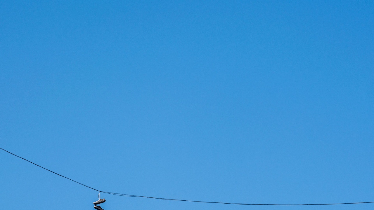 Кеды висят на проводе на фоне голубого неба