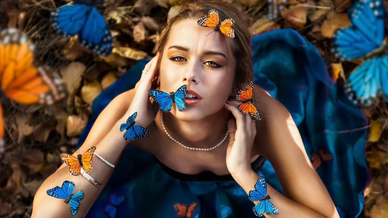Голубые и оранжевые бабочки на девушке