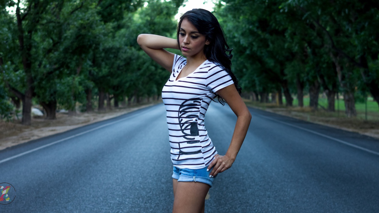 Брюнетка в джинсовых шортах среди дороги