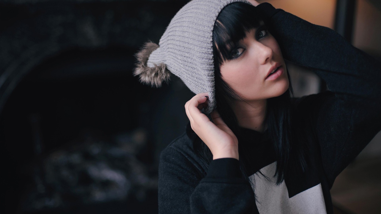 Брюнетка одевает вязаную шапочку