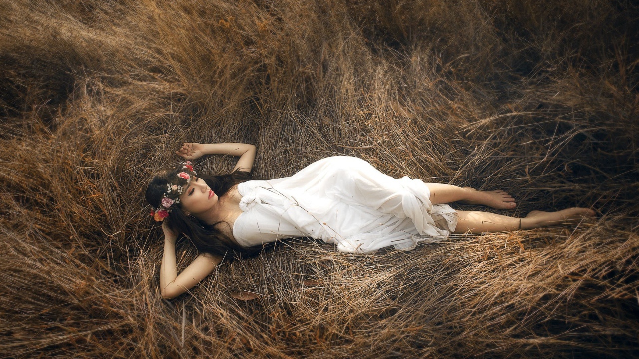 Девушка лежит на сухой траве
