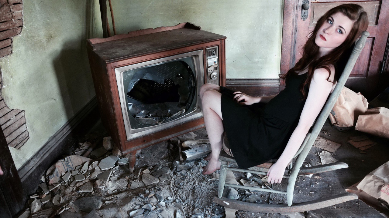 Girl sitting in the broken old TV