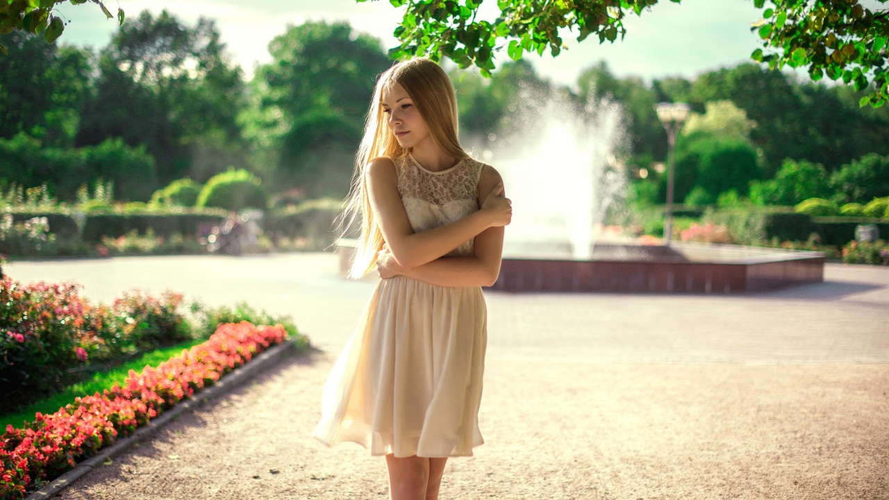 Блондинка в парке на фоне фонтана