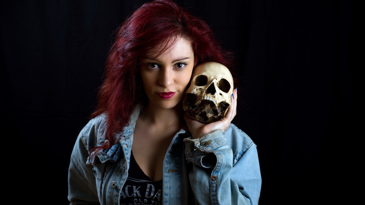 Девушка в джинсовой куртке держит череп на плече