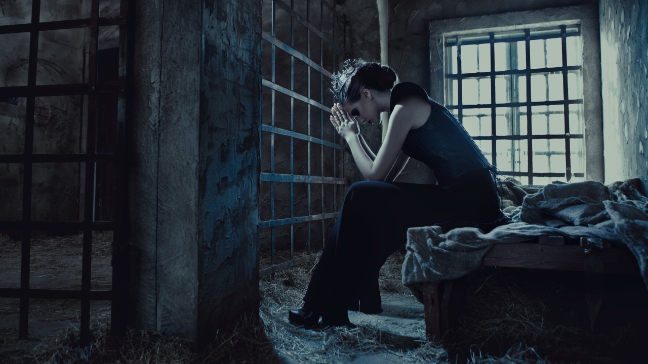 Девушка сидит за решеткой в тюрьме