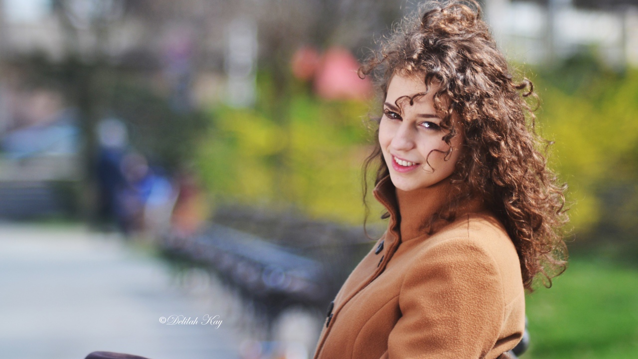 Ветер треплет волосы кучерявой девушки