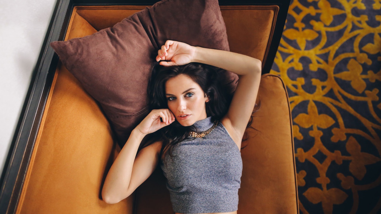 Модель Aurela Skandaj лежит на диване
