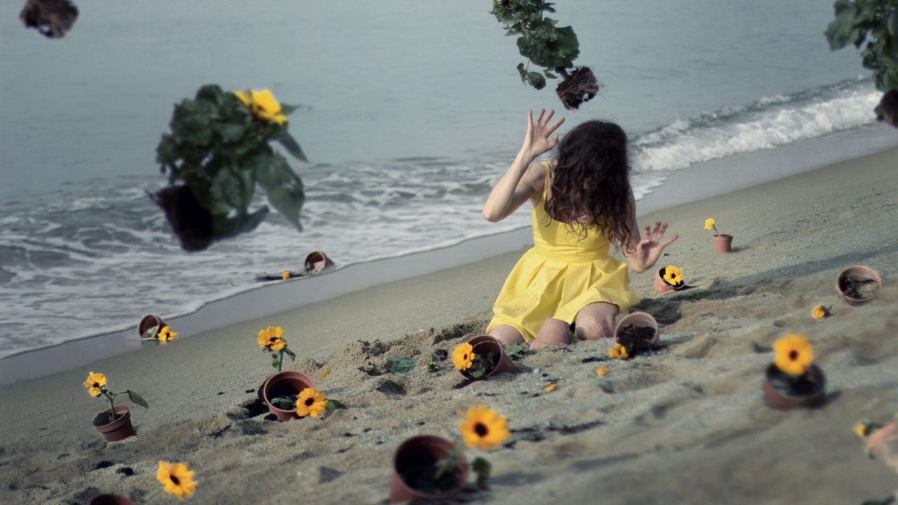 Модель в желтом платье среди цветов на пляже