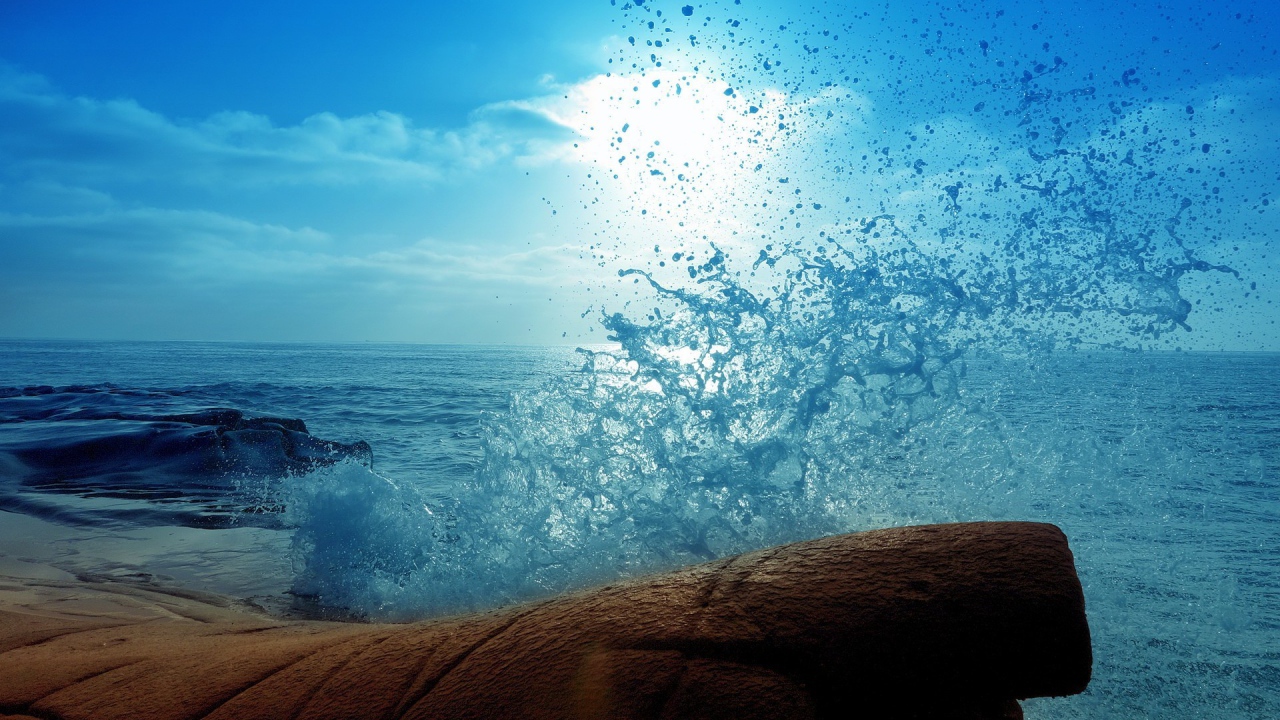 Голубая волна разбилась о камень на берегу
