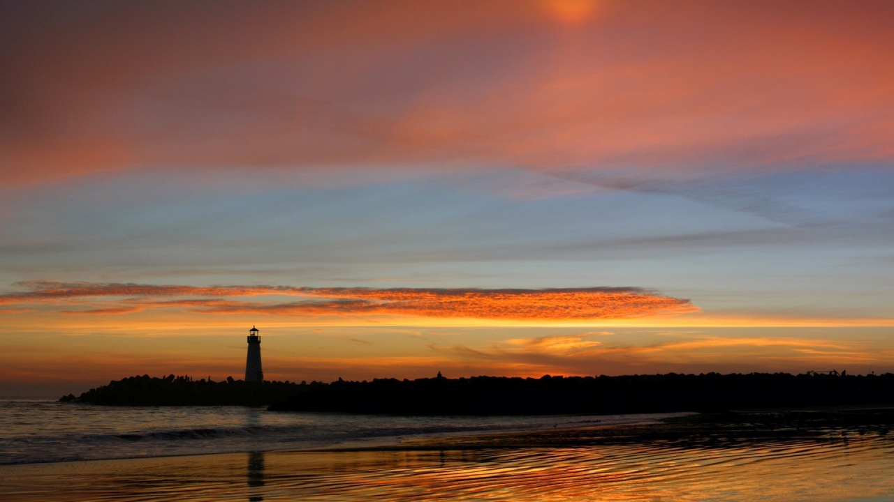 Силуэт маяка на фоне оранжевых облаков