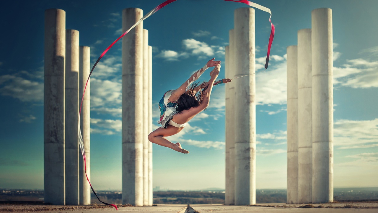 Гимнастка с лентой на фоне колонн