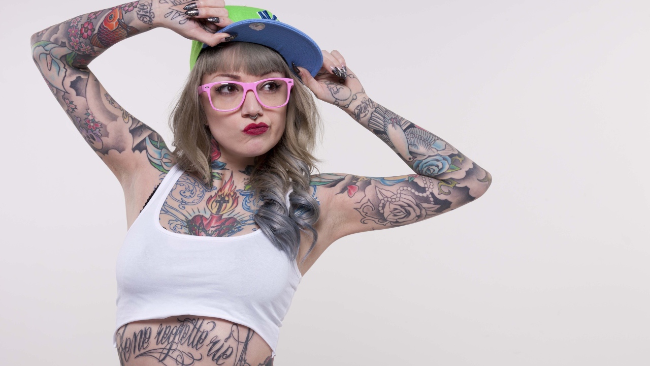 Tattooed woman in a cap and pink glasses